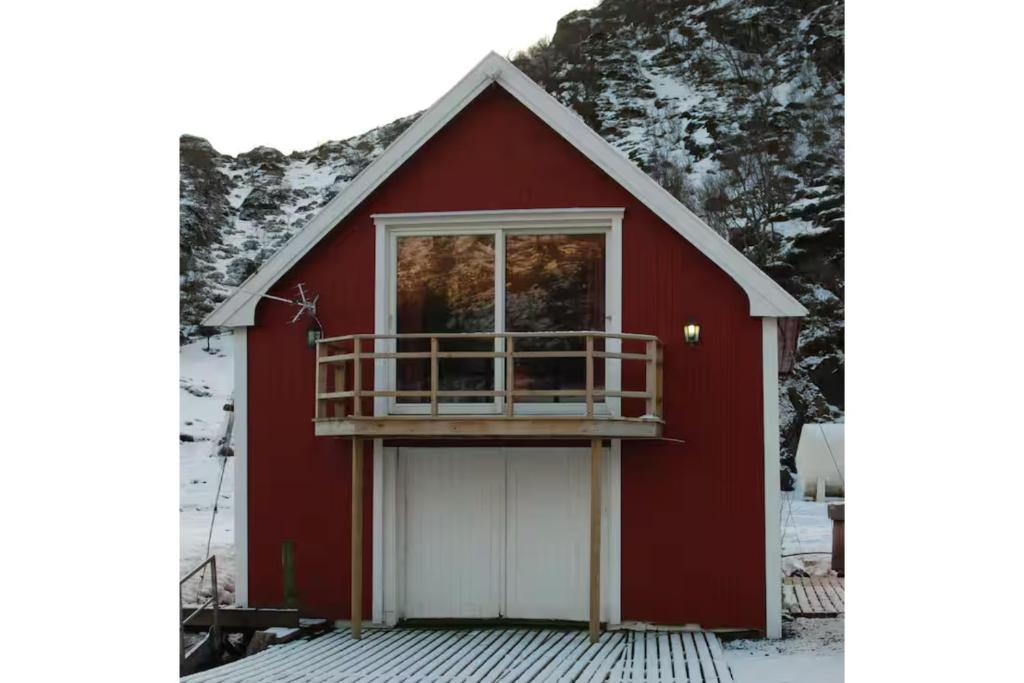 een rode schuur met een witte deur en een balkon bij Larsen Rorbu Lofoten in Napp