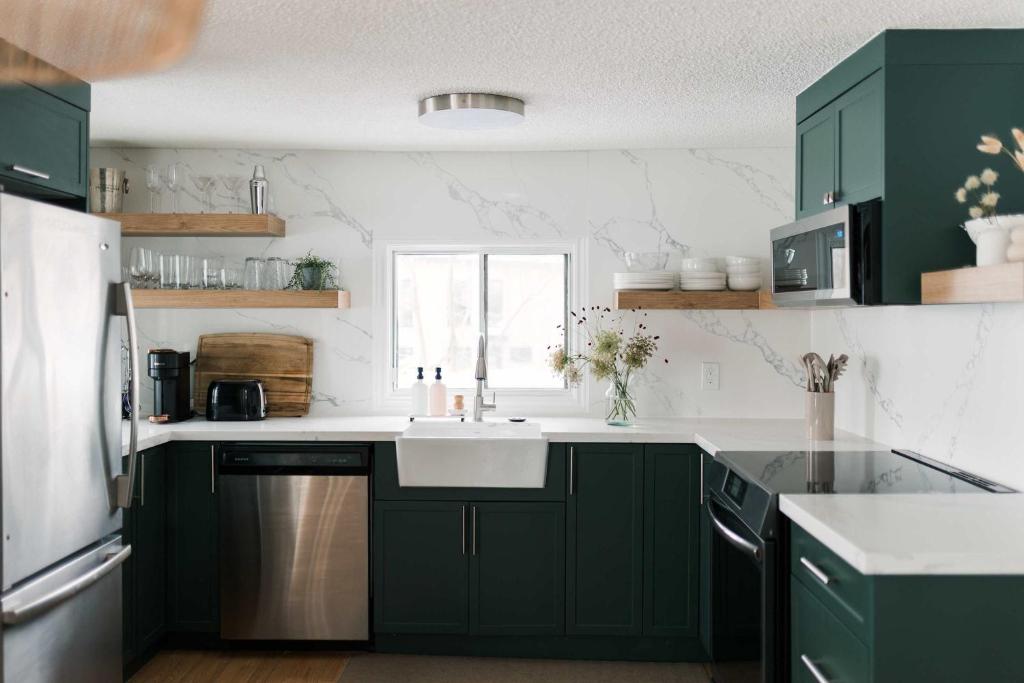 een keuken met groene kasten en een spoelbak bij Narrows Nook - Prince Edward County Waterfront in Deseronto