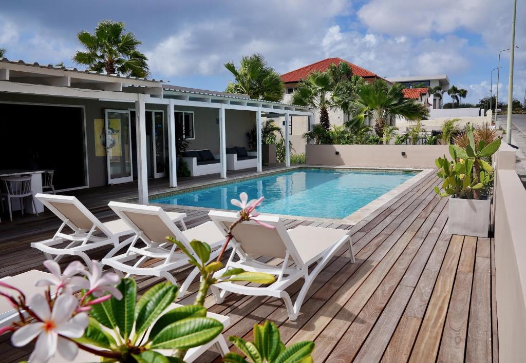 eine Terrasse mit weißen Stühlen und einem Pool in der Unterkunft Boutique Hotel & apartments JT Curaçao in Willemstad