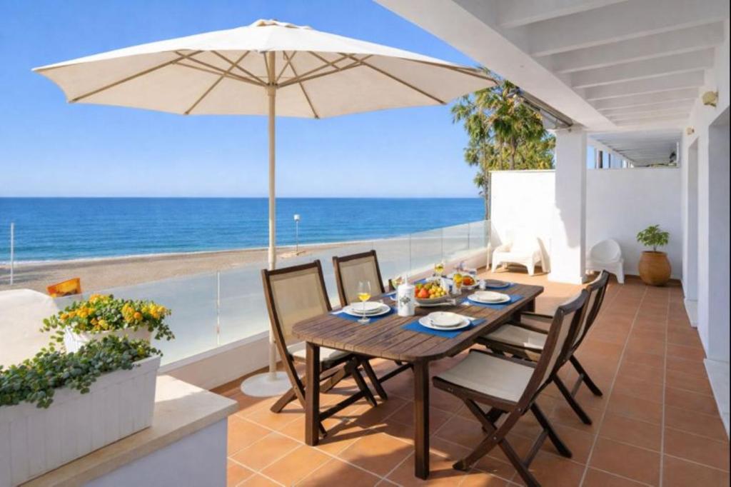 Ein Tisch mit Stühlen und einem Sonnenschirm auf einer Terrasse mit Meerblick in der Unterkunft Apartamentos Varadero sea view in La Cala del Moral