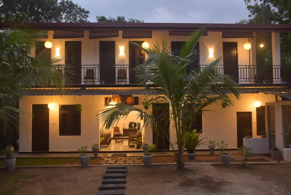 a house with a palm tree in front of it at Coco Villa Udawalawe in Udawalawe