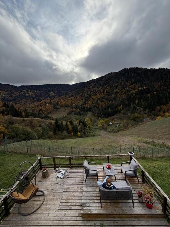a person laying on a chair on a wooden deck at Mitarbi Silence - cozy holiday cottages in mountains 