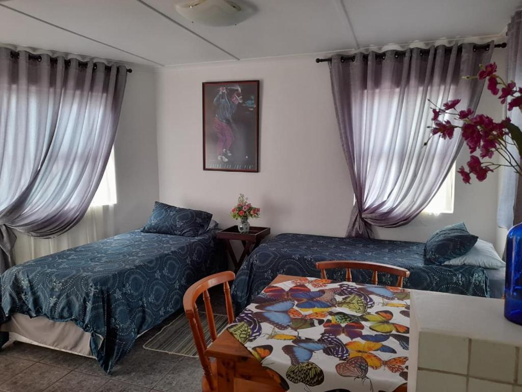 een slaapkamer met 2 bedden en een tafel met een tafel bij Benguela B&B in Richards Bay