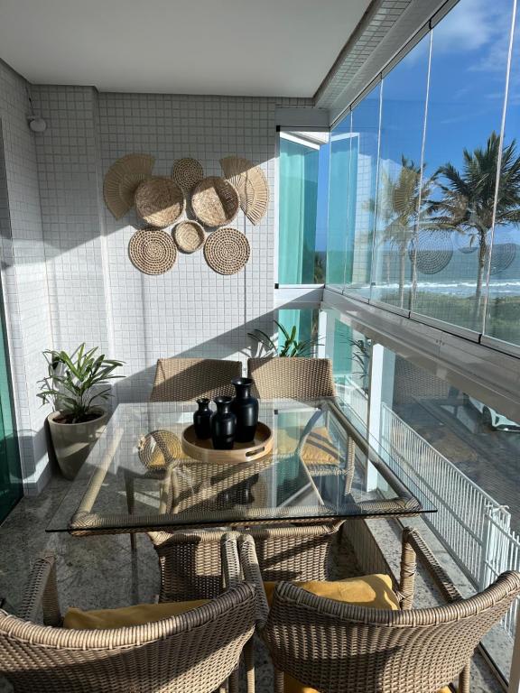 a glass table and chairs on a balcony with the ocean at 4 ILHAS, 2 SUITES, 2 GARAGENS in Bombinhas