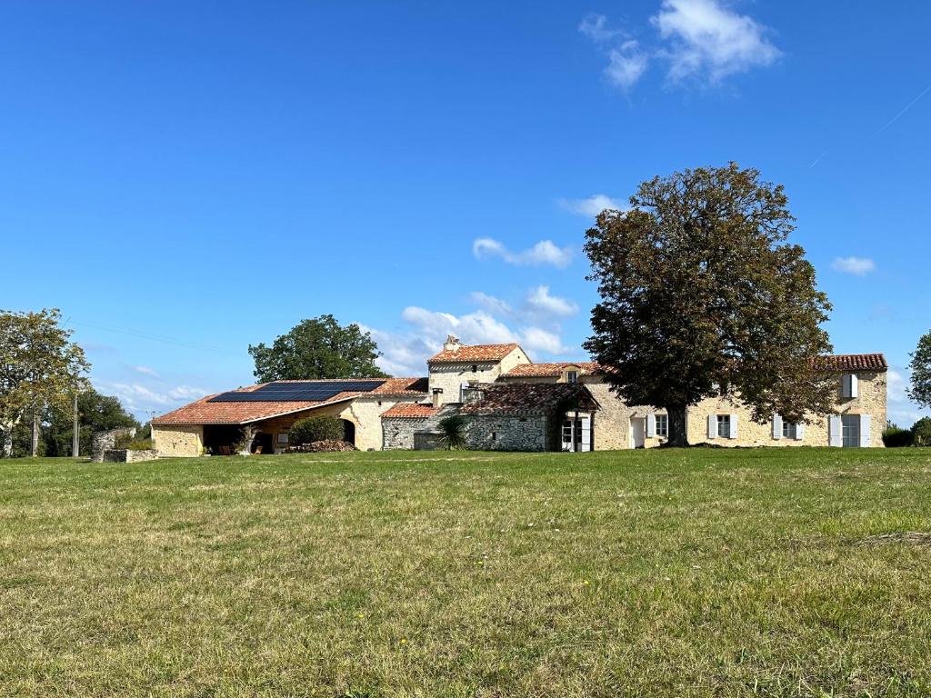 una vecchia casa di pietra in un campo con un albero di Chambre en pierre a Blanquefort-sur-Briolance