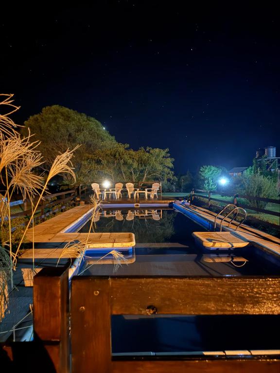 a boat deck with tables and benches at night at Cabañas El Atalaya in Villa Rumipal