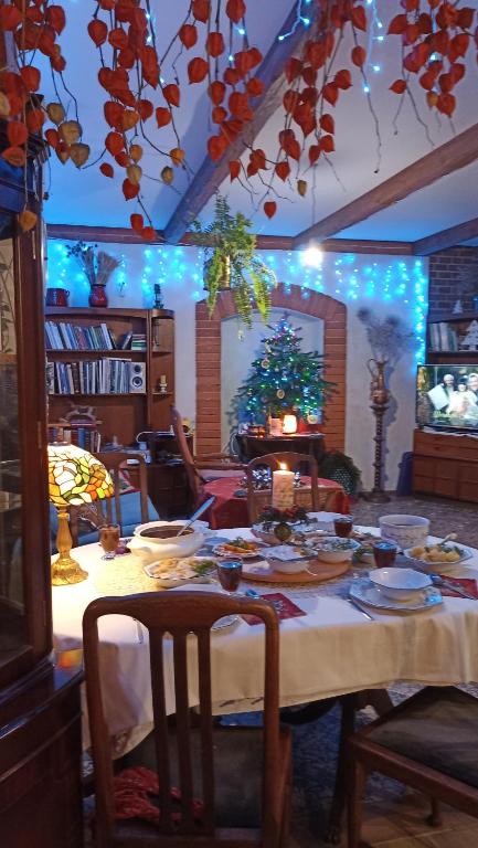a dining room table with a white tablecloth and blue lights at Dom Pod Złotym Bażantem in Kobiela