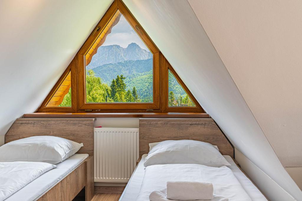 two beds in a room with a large window at Willa Serafin-basen, sauny i jacuzzi w Willa Baciarka dodatkowo płatne in Kościelisko