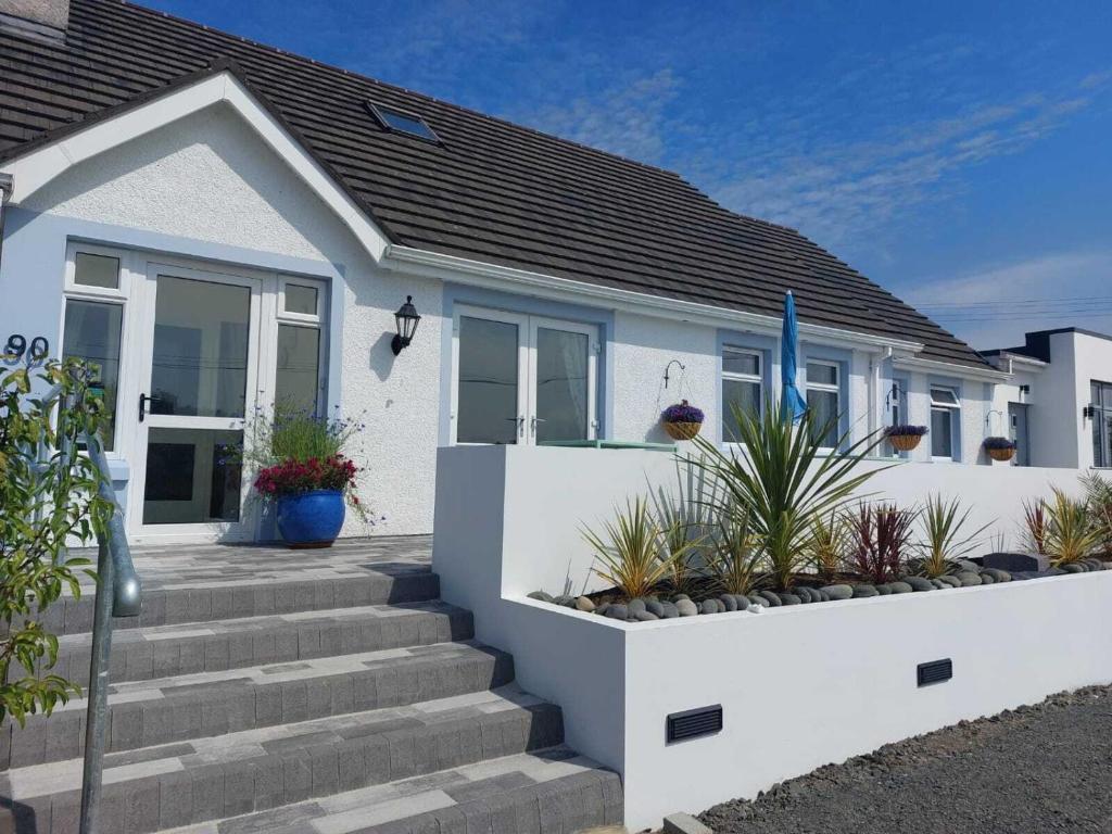een wit huis met een trap ervoor bij Rest a While in Bushmills