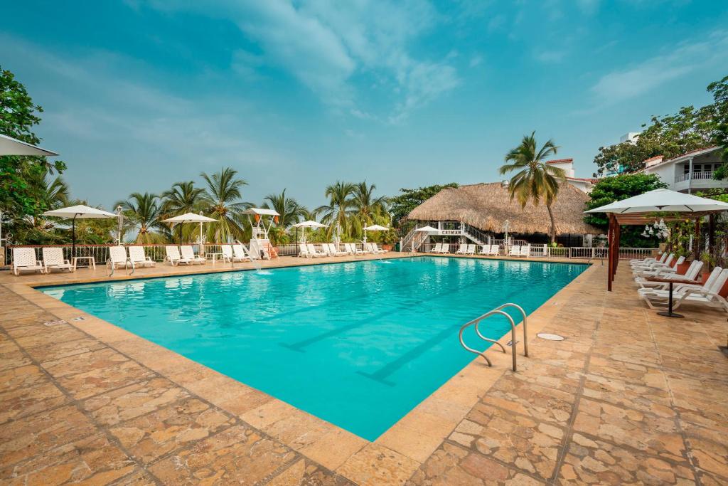 - une piscine avec des chaises et des parasols dans un complexe dans l'établissement Decameron Galeon - All Inclusive, à Santa Marta