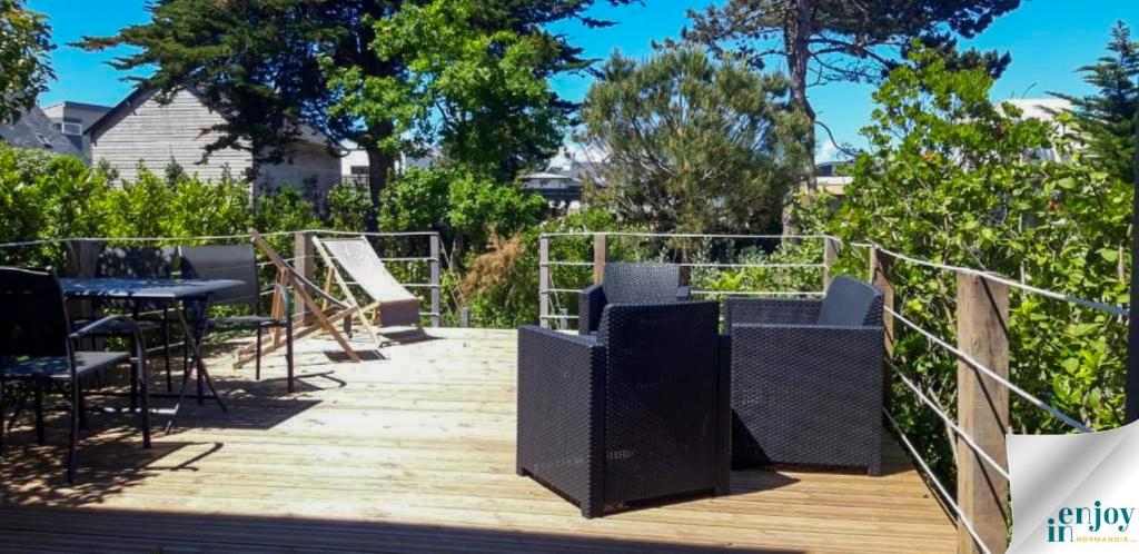 a wooden deck with a table and chairs on it at Villa Jules Petit Gîte in Agon Coutainville