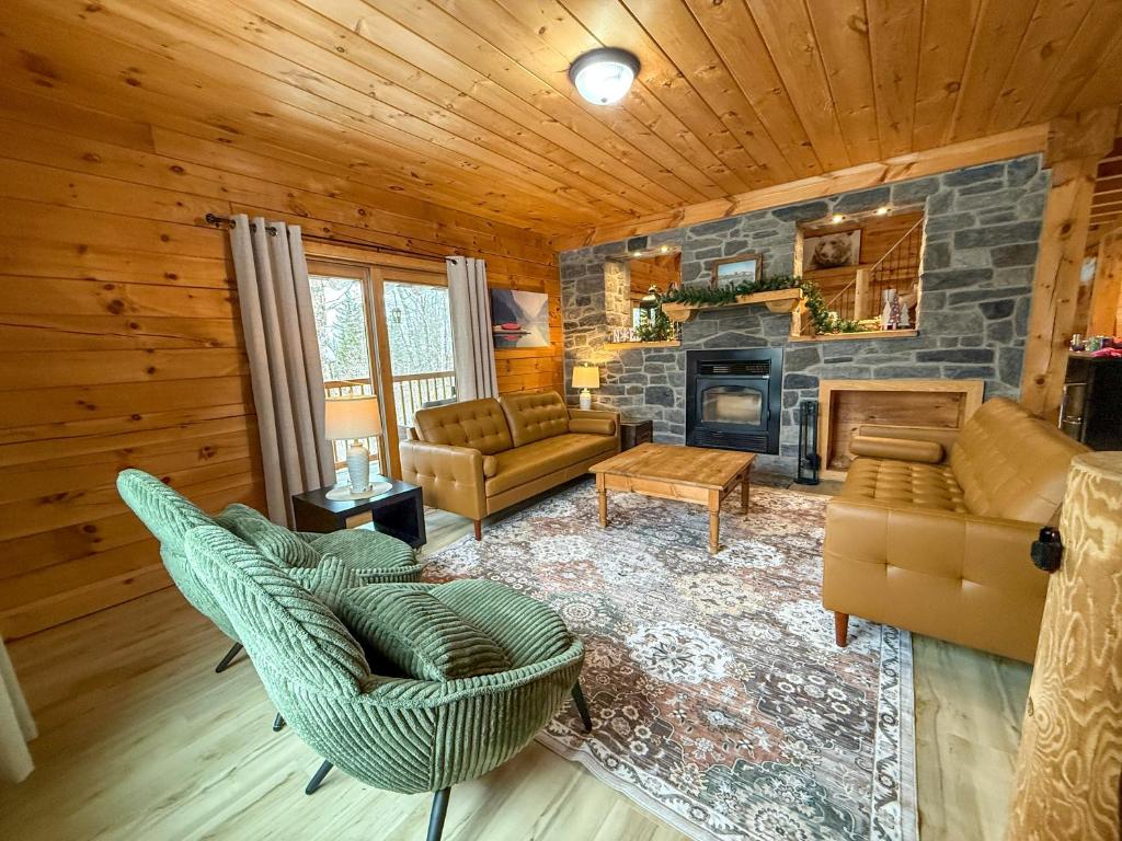 a living room with furniture and a stone fireplace at Chalet La Source Rouge in Saint-Raymond