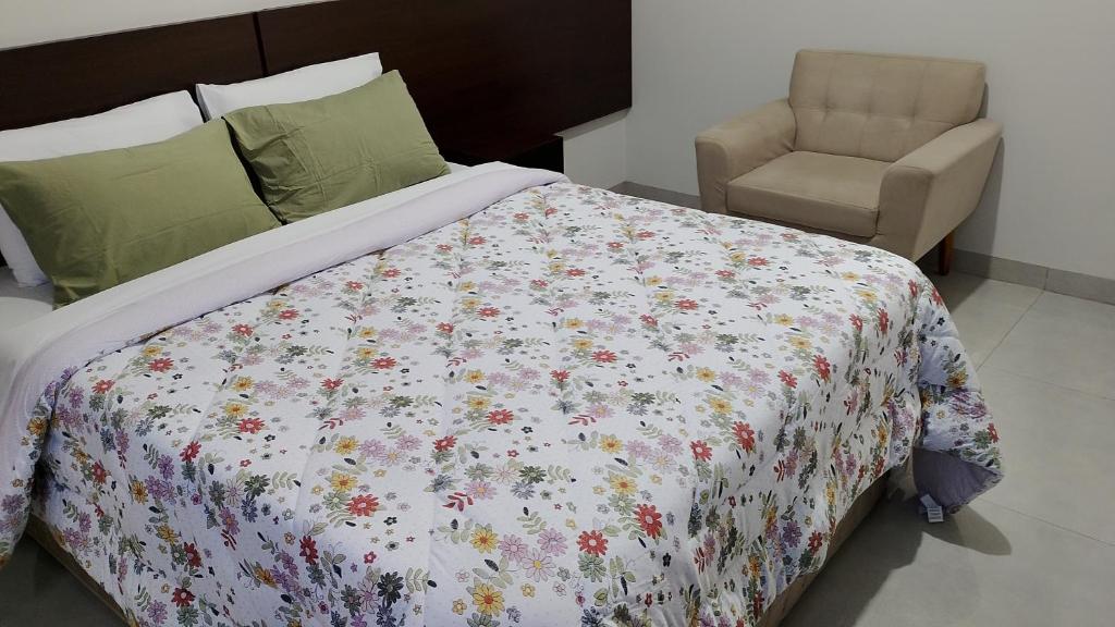 1 Schlafzimmer mit einem Bett mit Blumenbettdecke und einem Stuhl in der Unterkunft Hotel Villa Rica in Cassilândia