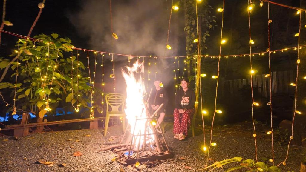 Zwei Personen stehen neben einem Feuer in einem Hof. in der Unterkunft Vihara Inn Resort in Vayittiri
