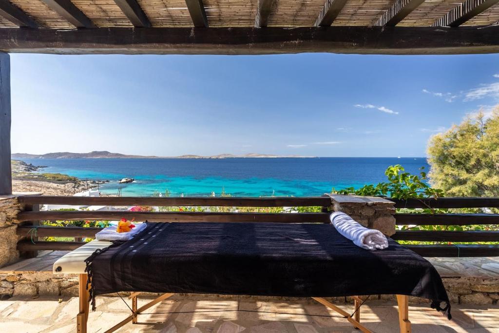 a bed on a balcony with a view of the ocean at Villa Macaro with Direct Beach Access in Mikonos