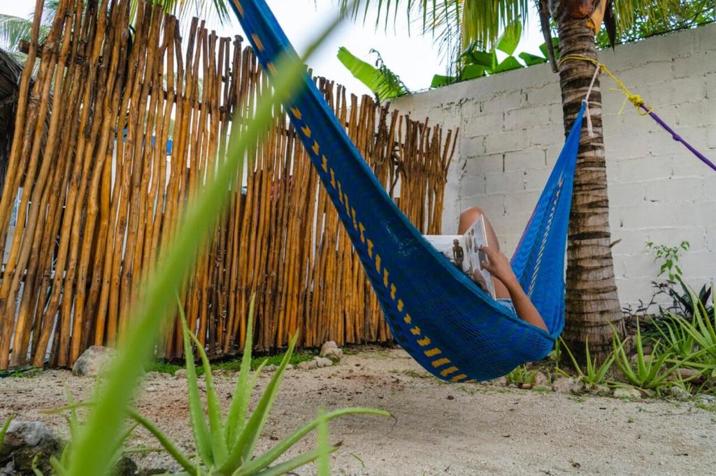 Eine Person sitzt in einer Hängematte neben einem Zaun in der Unterkunft Casa Nido Bacalar in Bacalar
