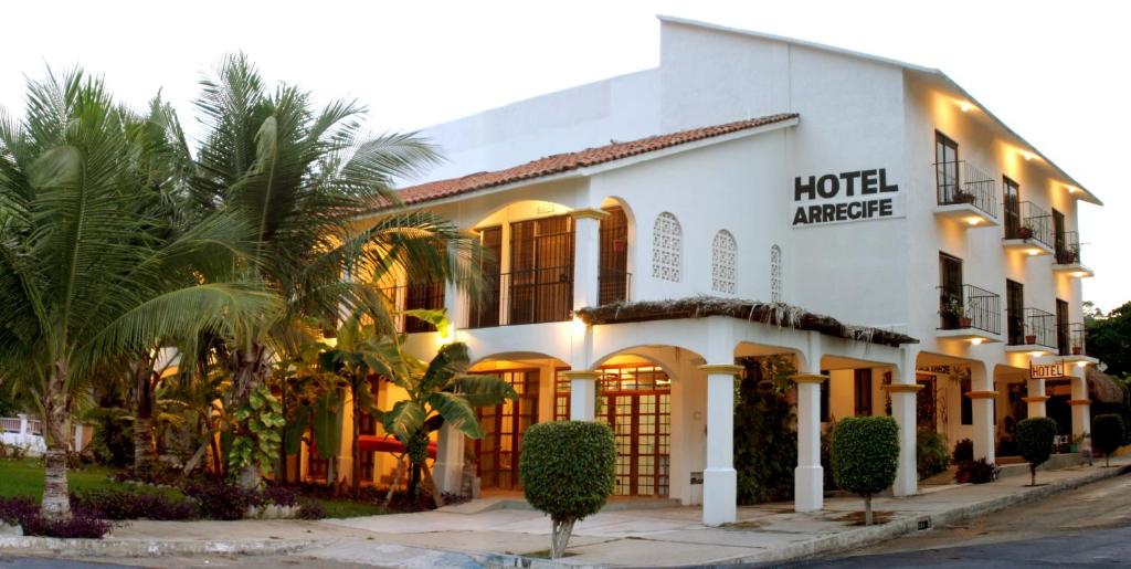 a hotel entrance with palm trees in front of it at Hotel Arrecife Huatulco Plus in Santa Cruz Huatulco