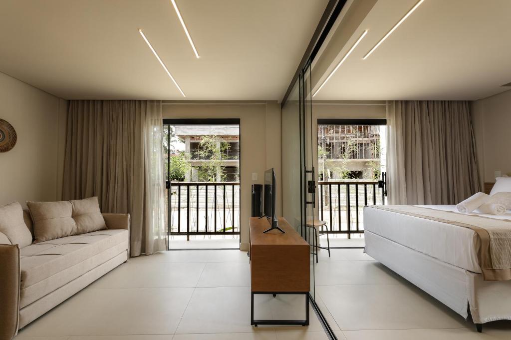 una camera da letto con un letto e un divano di Jubarte Flats a Itacaré