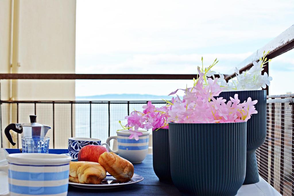 Ein Tisch mit einem Teller Essen und Vasen mit Blumen in der Unterkunft 3palme in Follonica