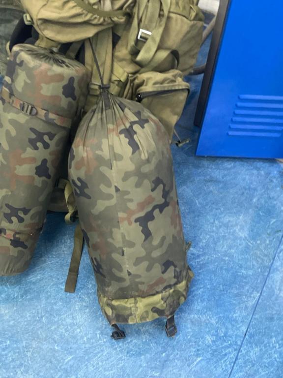 een persoon in camouflagekleding die naast een tas zit bij Nie wiem in Warschau