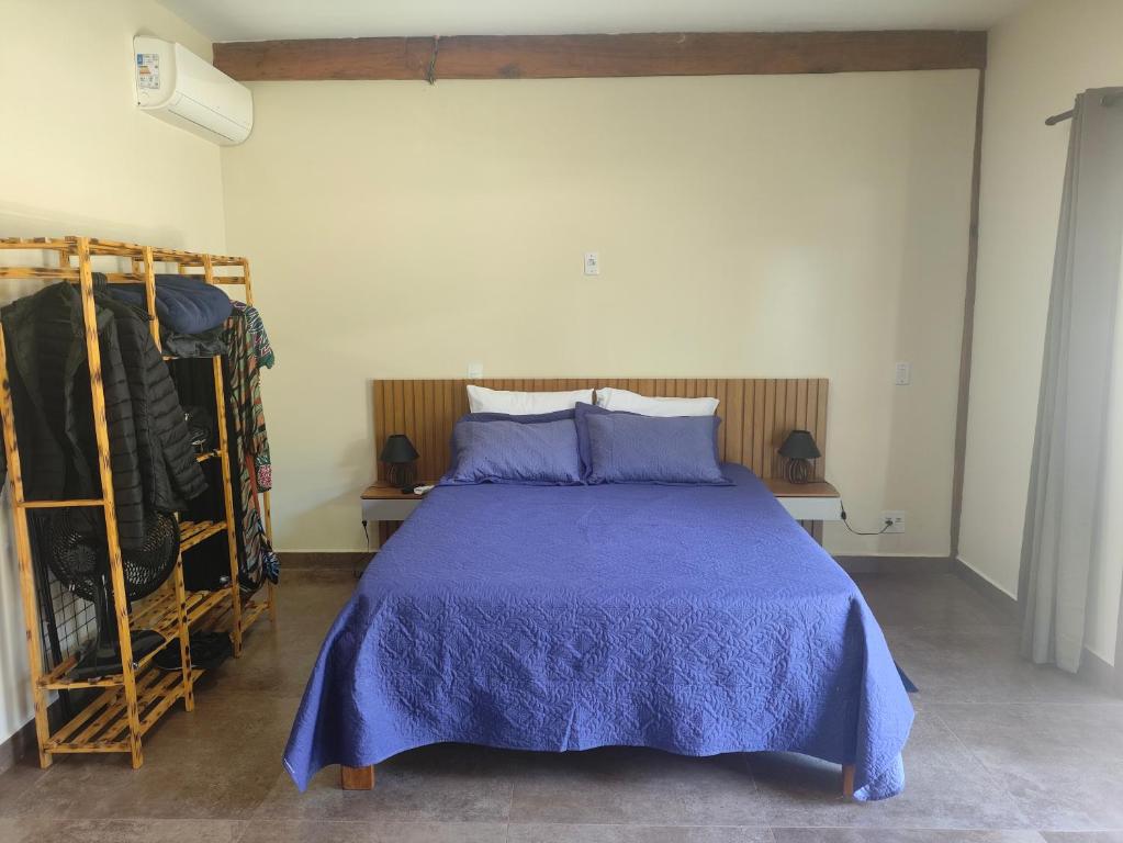 una camera da letto con un letto con un piumone blu di Trilha das Siriemas a Tiradentes