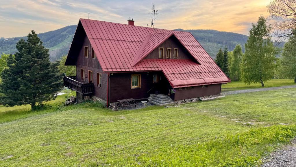 a house with a red roof on a green field at Penzion Soukupovi in Strážné