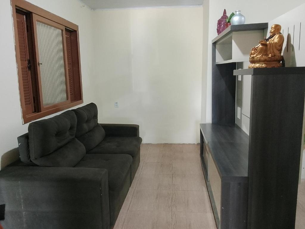 een woonkamer met een bank en een spiegel bij Kitnet com garagem e Wi-Fi in Tramandaí