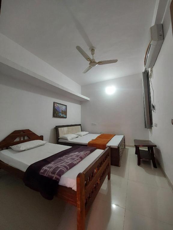 a bedroom with two beds and a ceiling fan at SOU Mahadev Homestay in Garudeshwar