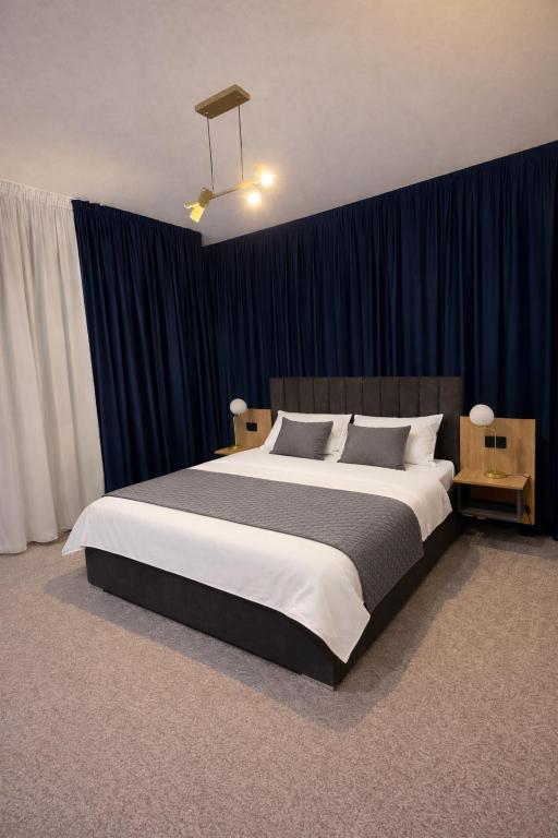 a bedroom with a large bed with blue curtains at Elmax Aparthotel in Craiova