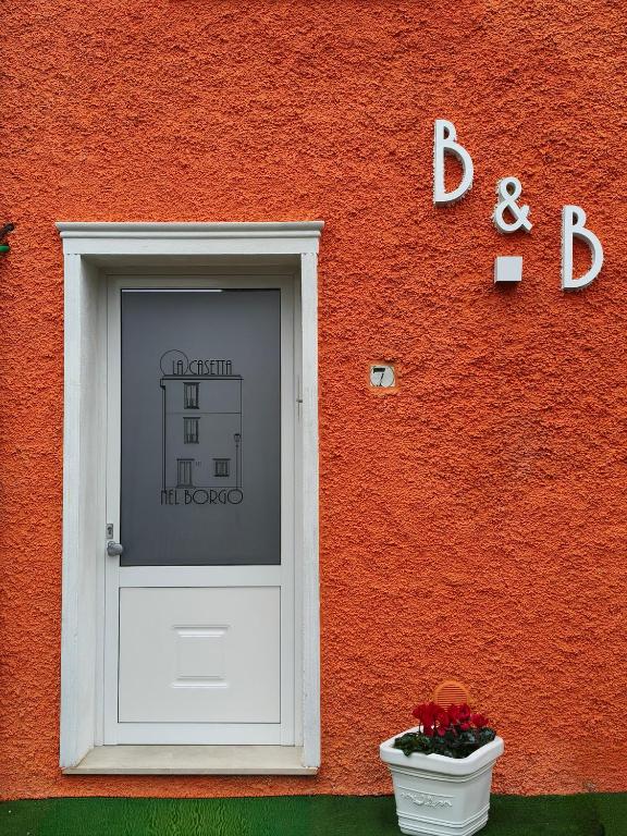 a red building with a white door and a window at La Casetta nel Borgo in Cerisano