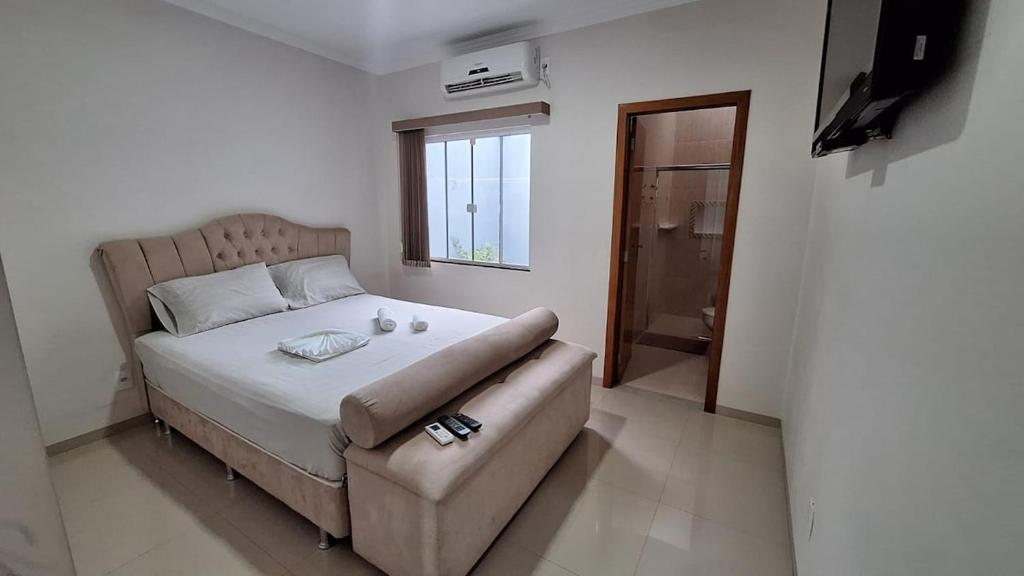 a bedroom with a bed and a couch and a window at Casa Requinte in Cascavel