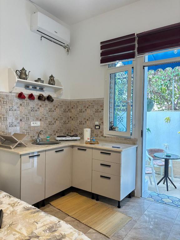 een keuken met witte kasten en een tafel en een raam bij Marsa Cocon Cozy in La Marsa Beach in La Marsa