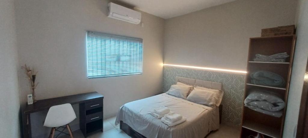 una piccola camera da letto con un letto e una scrivania di Casa Buritis a Primavera do Leste