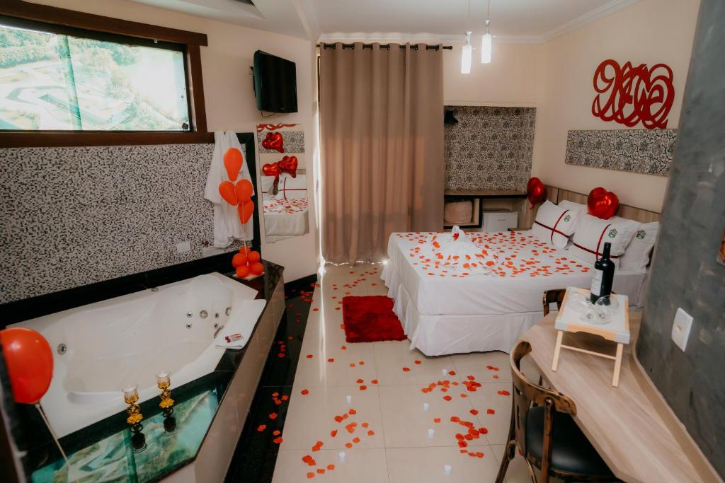 a room with two beds and a bathtub and a bedroom at Estrada Real Palace Hotel in Brumadinho