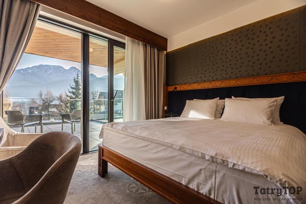 een slaapkamer met een groot bed en een balkon bij TatryTop Giewont House in Kościelisko