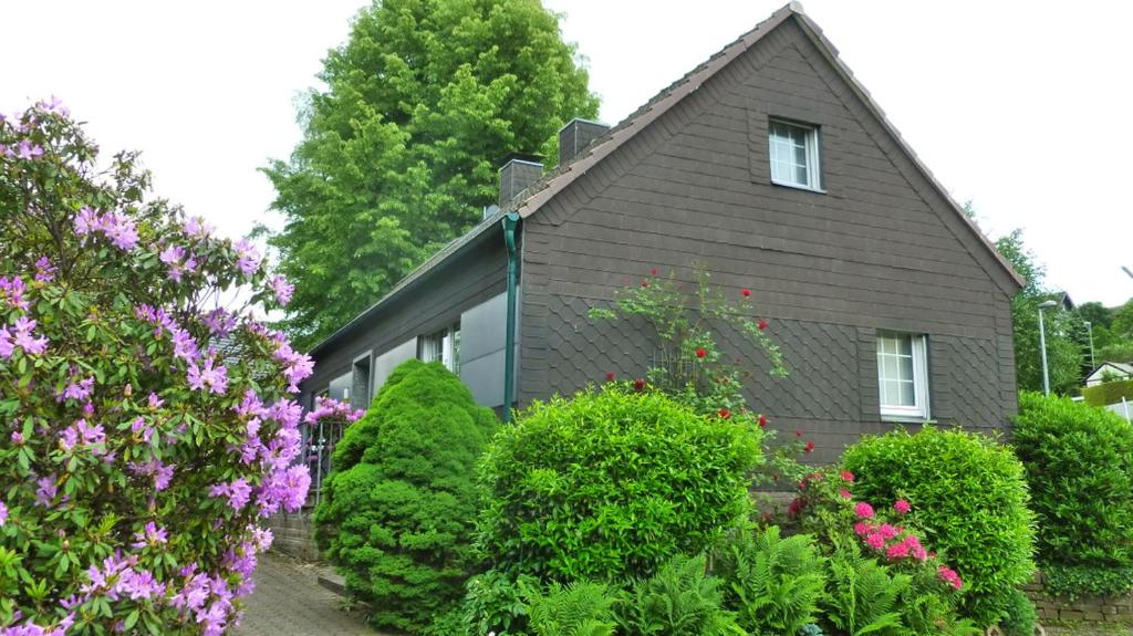 een huis met struiken en bloemen ervoor bij Gästehaus 1A in Lindlar
