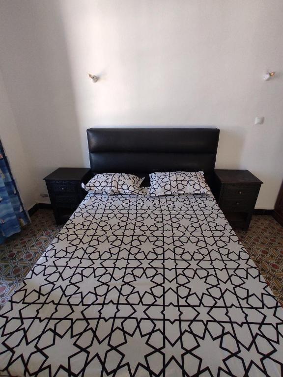 a bedroom with a bed with a black and white comforter at Appartement 3 pièces in LʼAgha