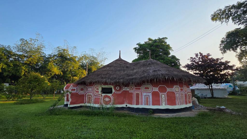 ein rotes Haus mit Strohdach auf einem Feld in der Unterkunft OneSeasonFarm in Chiang Saen