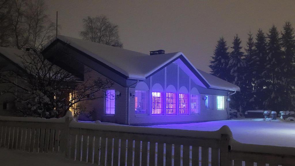 een huis verlicht met paarse lampen in de sneeuw bij Arctic Luxe Retreat in Rovaniemi