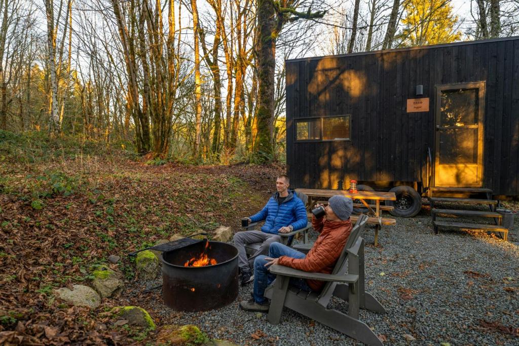 two men sitting on a bench next to a campfire at Postcard Cabins Skagit Valley, Outdoor Collection by Marriott Bonvoy in Mount Vernon