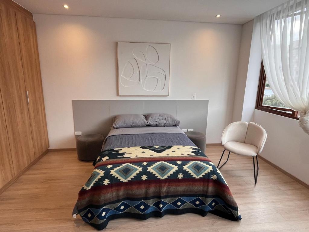 a bedroom with a bed and a chair in it at Nuevo y moderno departamento Quito Norte in Quito