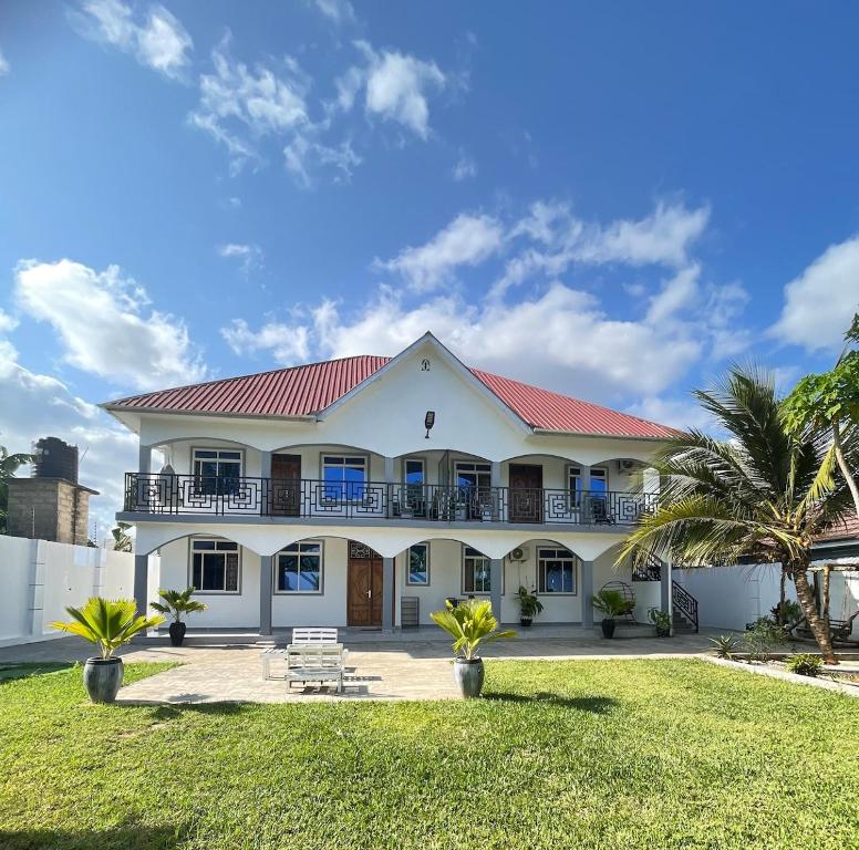 een groot wit huis met een rood dak bij HalmaHome Two Bedroom Apartment in Zanzibar City