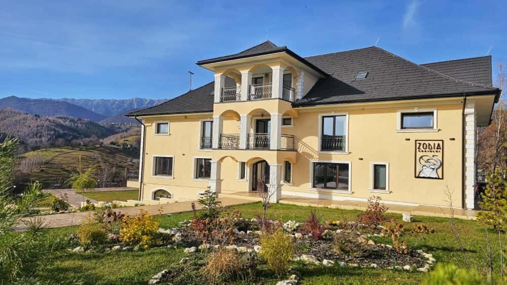 een groot geel huis bovenop een heuvel bij Zodia Craiului in Peştera