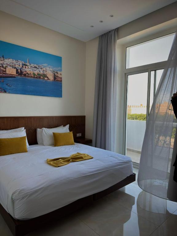 a bedroom with a bed and a large window at Hôtel Majestic Rabat Centre in Rabat