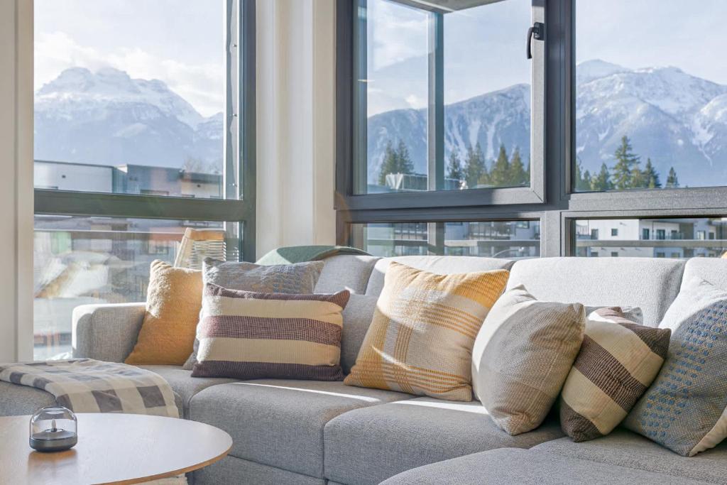 a couch with pillows on it in a room with windows at Cedar Vista - condo with stunning mountain views in Revelstoke