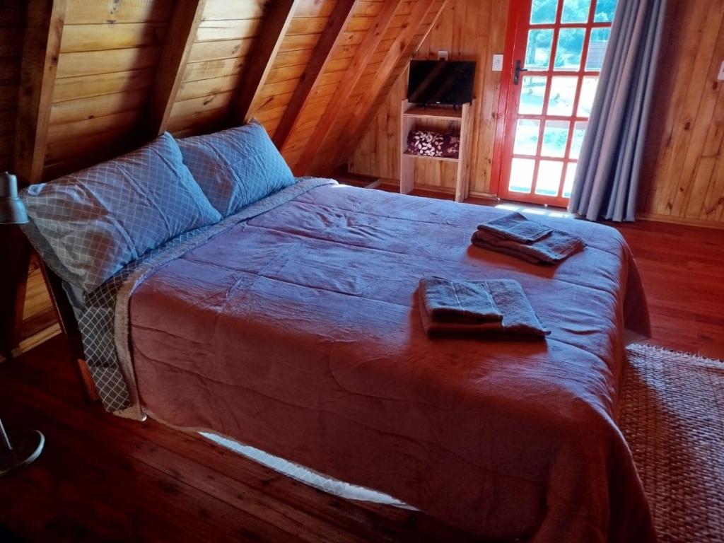 ein Schlafzimmer mit einem großen Bett in einer Hütte in der Unterkunft Refúgio Serrano in São Francisco de Paula