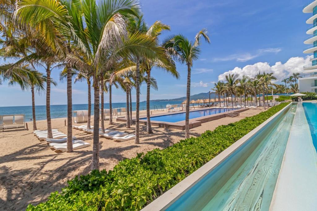 a swimming pool with palm trees and the beach at Modern Ocean View Apartment Private Balcon in Nuevo Nayarit