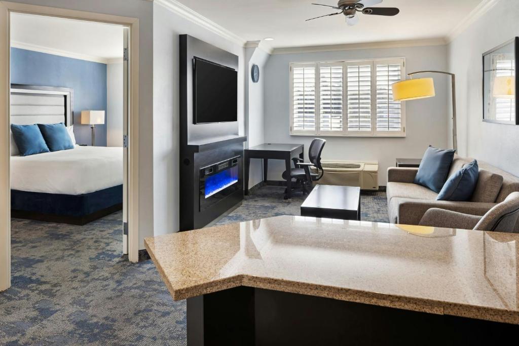 a hotel room with a bed and a living room at City Express by Marriott Manhattan Beach in Manhattan Beach