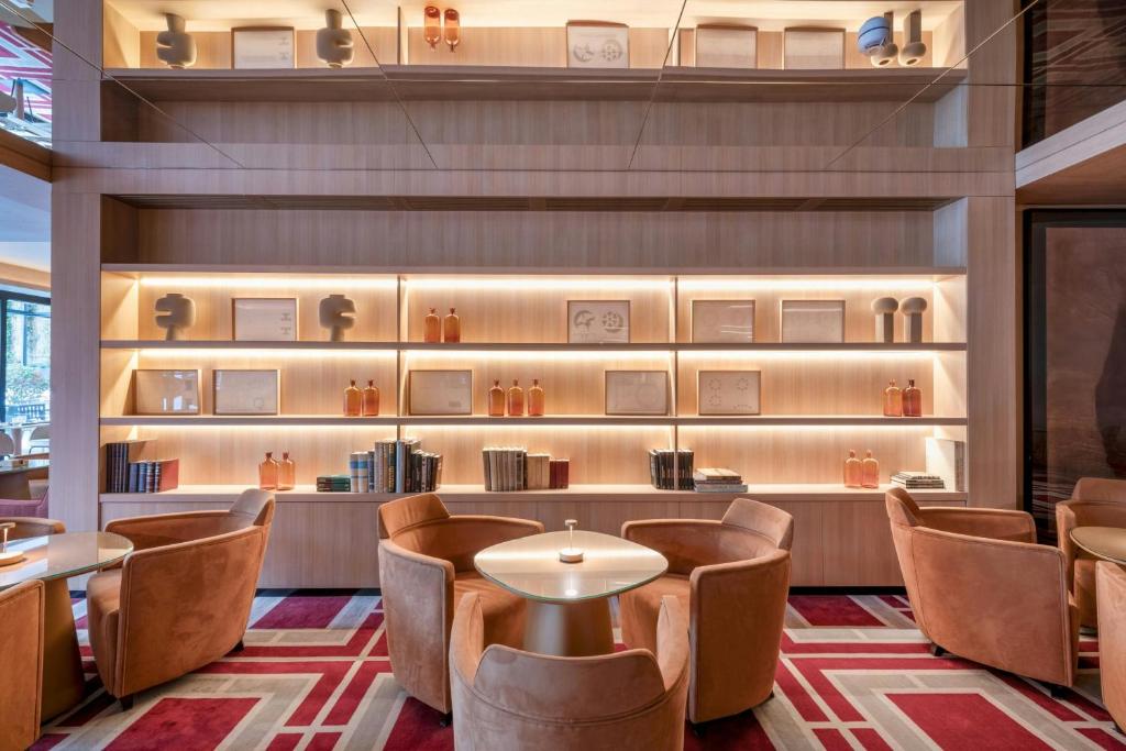 un restaurant avec une table, des chaises et une étagère avec des livres dans l'établissement AC Hotel Atocha by Marriott, à Madrid