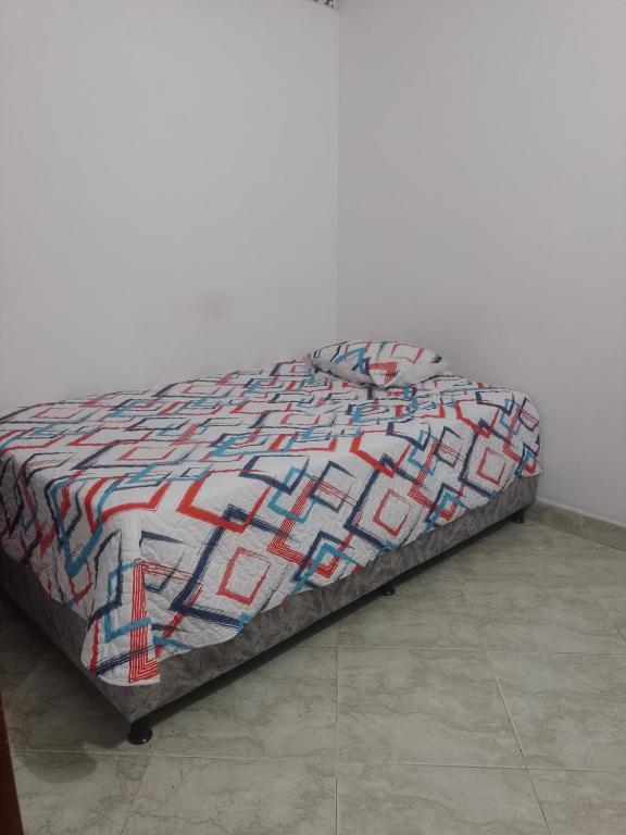 a bed with a colorful quilt on top of it at Apto central 3 hab in Apartadó
